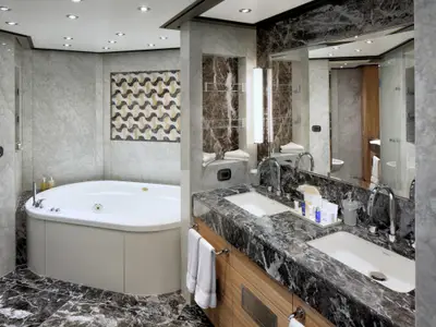Das luxuriöse Badezimmer in einer Suite an Bord der Zuiderdam zeigt einen Whirlpool und ein Doppelwaschbecken aus Marmor.
