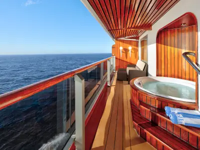 Balkon der Pinnacle Suite an Bord der Zuiderdam mit einem Whirlpool, einer gemütlichen Sitzecke und Blick auf das blaue Meer.