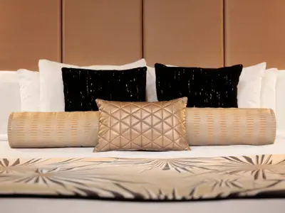 Detailansicht eines luxuriös gemachten Betts mit verschiedenen Zierkissen in einer Suite an Bord der Zuiderdam