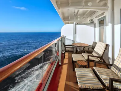 Einladender, großer Balkon einer Signature Suite an Bord der Zuiderdam mit bequemen Liegestühlen und freiem Blick auf das tiefblaue Meer.
