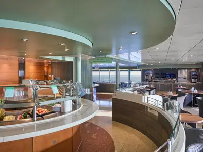 Blick in das helle Buffet-Restaurant La Brasserie an Bord der MSC Armonia mit frischem Obst und Tischen mit Meerblick.