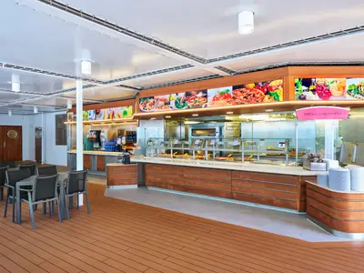 Der helle Pizza & Pasta Buffetbereich an Bord der MSC Armonia, mit mehreren Servierstationen, warmer Beleuchtung und modernen Sitzgelegenheiten. Im Hintergrund runde Holztüren.