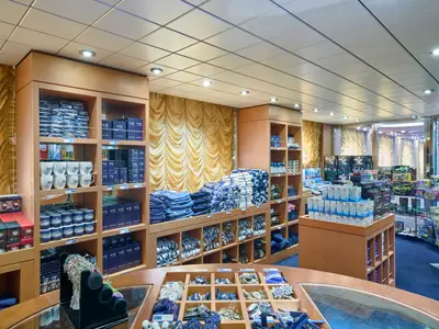 Ein heller und gut gefüllter Logo Shop an Bord der MSC Armonia mit Regalen voller MSC-Markenartikel wie Tassen, Kleidung, Souvenirs und Spielzeug.