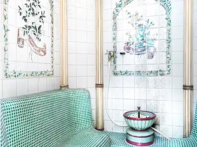 Dampfbad im MSC Aurea Spa an Bord der MSC Armonia. Weiße Fliesenwände mit Jasmin- und Kamille-Motiven, grüne Mosaikbank, Duscharmatur, Schale.