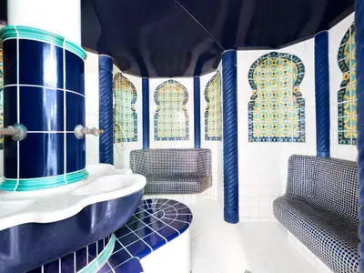 Ein Dampfbad im MSC Aurea Spa an Bord der MSC Armonia mit blauen Säulen, gewölbten Kacheln und Sitzbänken aus Mosaiksteinen in einem marokkanisch inspirierten Design.