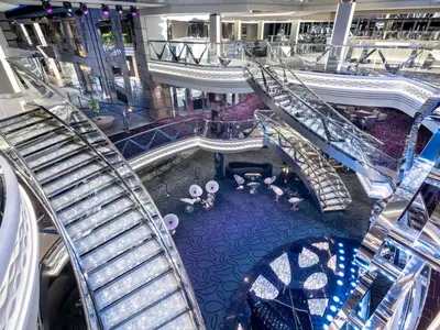 Vogelperspektive auf das opulente Infinity Atrium der MSC Bellissima. Funkelnde Swarovski-Kristalltreppen, elegante Lounges und glänzende Oberflächen prägen das moderne Design. Die mehrstöckige Halle lädt zum Verweilen ein.