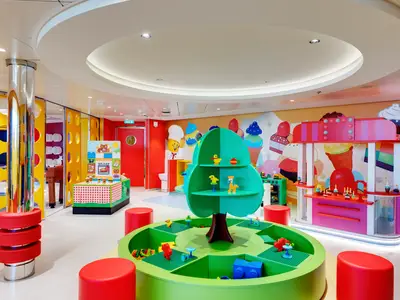 Der farbenfrohe Mini Club an Bord der MSC Bellissima mit Lego-Spieltischen, einer Spielküche und einer Eisdiele. Bunte Wände und Möbel schaffen eine spielerische Umgebung für Kinder.