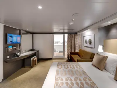 Eine modern eingerichtete Premium Suite Aurea an Bord der MSC Bellissima. Sie zeigt ein Doppelbett, ein Sofa, einen Schreibtisch und einen Balkon mit Aussicht.