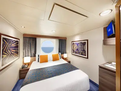 Geräumige Junior Aussenkabine an Bord der MSC Divina. Ein Doppelbett, Bullauge mit Meerblick, zwei Nachtschränke und ein TV sind zu sehen. Die Kabine ist modern und gemütlich eingerichtet.