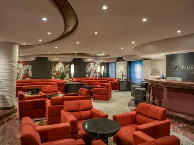 Die Divina Bar an Bord der MSC Divina mit bequemen roten Samtsesseln und langen Sofas. Eine elegante Bar und ein Buffet sind sichtbar. Keine Personen.