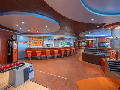 Innenansicht der lebhaften Sportsbar mit orangefarbener Theke, Barhockern, Sportscreens und einem Bowlingbereich an Bord der MSC Divina.