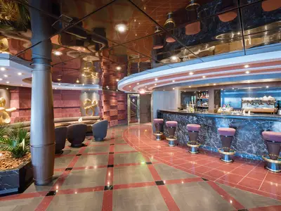 Die Top Sail Lounge an Bord der MSC Divina: Eine luxuriöse Bar mit glänzendem Marmorbartresen, bequemen Lounge-Sesseln und Goldskulpturen, alles unter einer reflektierenden Decke.