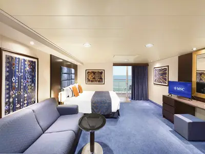 Geräumige, barrierefreie Balkonkabine der MSC Divina. Ein Doppelbett, Sofa und TV sind sichtbar, mit Zugang zu einem Balkon mit Meerblick am Tag.
