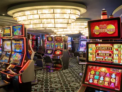 Mehrere beleuchtete Spielautomaten mit hohen Jackpots wie 88 Fortunes im Casinò Veneziano an Bord der MSC Divina. Elegante Kronleuchter und gemusterter Teppichboden ergänzen die Szene.
