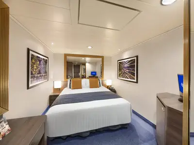 Eine gemütliche Innenkabine an Bord der MSC Divina mit einem Doppelbett, Nachttischen, Lampen und einem Fernseher. Kunstwerke an den Wänden.