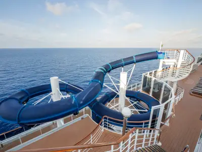 Blick von oben auf die dunkelblaue, kurvenreiche Wasserrutsche an Bord der MSC Divina, die über das Sonnendeck führt. Das weite Meer bildet den Hintergrund. Keine Personen sichtbar.