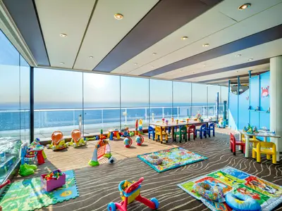 Der helle Doremiland Baby Club an Bord der MSC Divina bietet bunte Spielsachen, Tische und Stühle für Kinder, mit weitem Meerblick.
