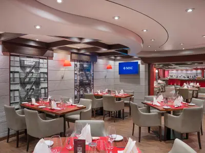 Das moderne Spezialitätenrestaurant Butcher's Cut der MSC Divina. Gedeckte Tische, bequeme Sessel, rote Wandleuchten und urbane Wandbilder.