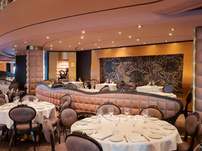 Im Restaurant 'The Black Crab' an Bord der MSC Divina: gedeckte Tische, elegante Stühle und Bänke. Wände mit Krabben-Kunstwerken.