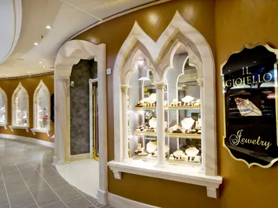 Blick in den luxuriösen Juwelierladen „IL GIOIELLO“ an Bord der MSC Divina. Mehrere gewölbte Schaufenster zeigen goldenen Schmuck in einer eleganten Umgebung mit goldenen Wänden und Marmorakzenten.