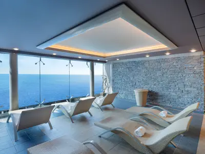 Der Thermalbereich des MSC Aurea Spa an Bord der MSC Divina bietet Liegestühle mit direktem Blick auf das offene Meer. Moderne Einrichtung mit Steinwand und stilvoller Beleuchtung lädt zur Entspannung ein.