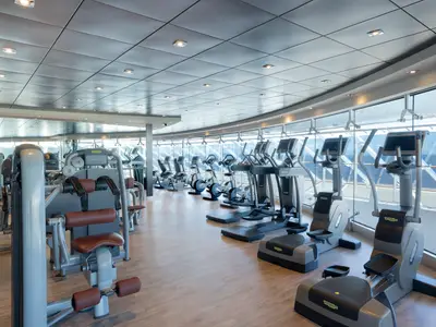 Modernes Fitnessstudio an Bord der MSC Divina mit Technogym-Geräten. Große Fensterfront bietet Meerblick. Helle Räume, ohne Personen.
