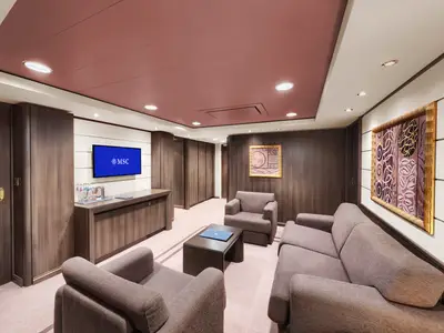Ein geräumiger und elegant eingerichteter Wohnbereich einer Suite an Bord der MSC Divina mit beigen Sofas, Sesseln, einem dunklen Couchtisch und einem Flachbildfernseher. Die Wände sind in dunklem Holz und hellen Paneelen gehalten, die Decke ist rotbraun mit integrierten Lichtern.