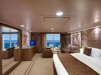Eine geräumige MSC Yacht Club Grand Suite an Bord der MSC Divina. Ein Kingsize-Bett und ein separater Wohnbereich mit Sofa und Sessel bieten Komfort. Der Balkon gewährt Meerblick. Eine elegante und komfortable Kabine auf See.