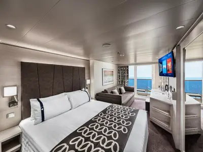 Moderne Balkonkabine an Bord der MSC Euribia. Grosses Doppelbett, Sofa-Sitzecke, TV und bodentiefe Fenster mit Meerblick. Die Einrichtung ist hell und elegant.