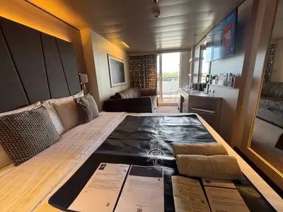 Blick in eine gemütlich eingerichtete Balkonkabine an Bord der MSC Euribia mit Doppelbett, Sofa und Balkon.
