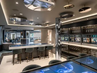 Ansicht des stilvollen Helios Wine Maker an Bord der MSC Euribia mit modernen Weindispensern, Barhockern, interaktiven Tischen und reflektierenden Elementen.