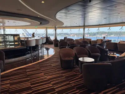 Blick in die moderne Bar-Lounge an Bord der MSC Euribia mit gemütlichen Sesseln und großen Panoramafenstern zum Meer.