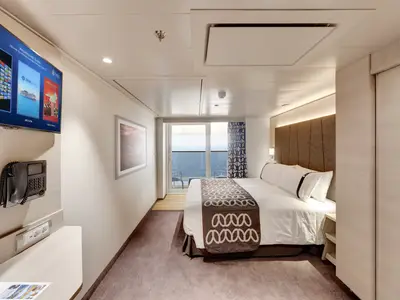 Moderne Balkonkabine der MSC Euribia mit Doppelbett und TV. Durch eine Glastür ist ein Balkon mit Meerblick sichtbar. Helle, elegante Einrichtung.