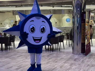 Das blaue, sternförmige Maskottchen Doremi posiert freundlich winkend an Bord der MSC Euribia.