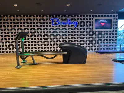 Eine moderne Bowlingbahn an Bord der MSC Euribia mit einem schwarzen Kugelrücklauf und einem blauen Bowling-Leuchtschriftzug.