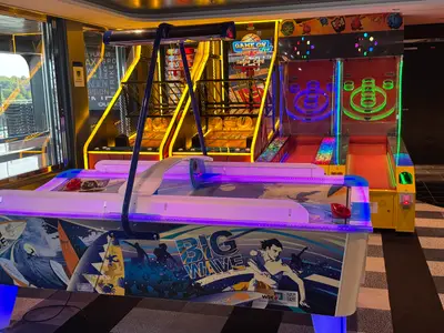 Der bunte Arcade-Bereich an Bord der MSC Euribia mit einem Airhockey-Tisch im Vordergrund und Basketball- sowie Skee-Ball-Automaten dahinter.