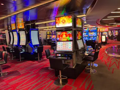 Blick in das bunt beleuchtete Casino an Bord der MSC Euribia mit Reihen von modernen Spielautomaten und roten Teppichböden.