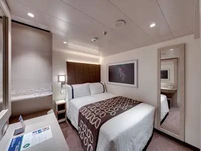 Geräumige Innenkabine an Bord der MSC Euribia mit Doppelbett, Schreibtisch und Ganzkörperspiegel. Die helle Einrichtung wird durch indirekte Beleuchtung akzentuiert.