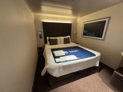 Blick auf das gemütliche Doppelbett in einer modernen Innenkabine an Bord der MSC Euribia.