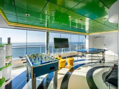 Der Young Club der MSC Euribia zeigt einen modernen Unterhaltungsbereich. Ein Tischkicker und Tischtennis stehen vor Panoramafenstern mit Meerblick. Grüne Decke, gemusterter Boden. Keine Personen.