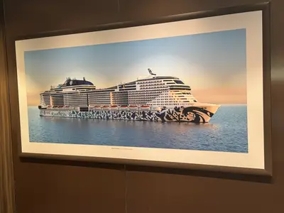 Ein gerahmtes Wandbild an Bord der MSC Euribia, das das Schiff auf ruhigem Meer bei Sonnenuntergang zeigt.