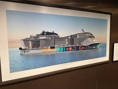 Ein gerahmtes Bild an einer Wand zeigt die Außenansicht der MSC Euribia auf dem Meer mit ihrer auffälligen, bunten Rumpfbemalung.