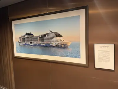 Ein gerahmtes Bild an Bord der MSC Euribia zeigt das Schiff auf dem Meer, daneben hängt eine Informationstafel.