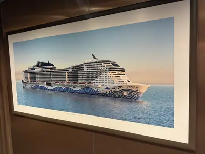 Ein gerahmtes Bild zeigt das Kreuzfahrtschiff MSC Euribia auf dem blauen Meer unter klarem Himmel.