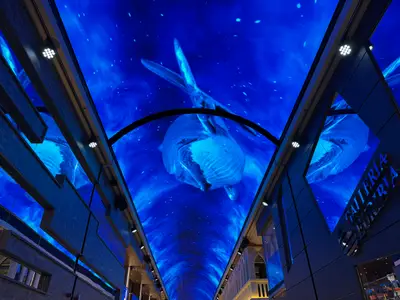 Blick nach oben an Bord der MSC Euribia auf die Galleria mit einem riesigen LED-Himmel, der einen blauen Wal zeigt.