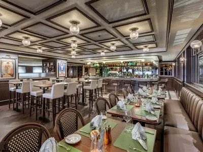 Blick in das elegant eingerichtete Spezialitätenrestaurant L'Atelier du Voyageur an Bord der MSC Euribia mit Tischen, Stühlen und einer gut gefüllten Bar.
