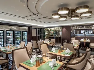 Innenansicht des eleganten Spezialitätenrestaurants Le Grill an Bord der MSC Euribia, mit stilvoll gedeckten Tischen, bequemen Stühlen und beleuchteten Weinkühlern. Im Hintergrund ist ein Barbereich sichtbar.