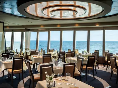 Das elegante Restaurant Colorado River an Bord der MSC Euribia bietet Tische mit weissen Tischdecken und Blick auf das weite Meer durch grosse Fenster.