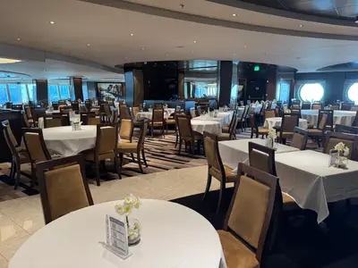 Ein Blick in das elegante, großzügig gestaltete Hauptrestaurant an Bord der MSC Euribia mit eingedeckten Tischen und braunen Polsterstühlen.