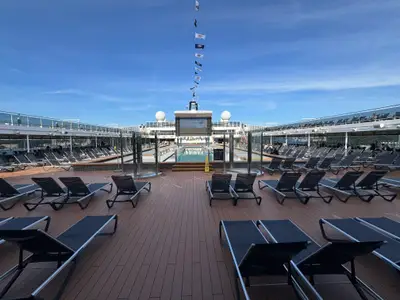 Blick über das sonnige, leere Sonnendeck mit zahlreichen Liegen und dem Poolbereich an Bord der MSC Euribia.
